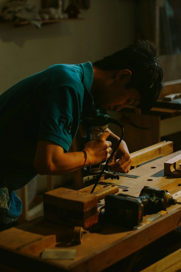 Carpenter using a router on wood in workshop